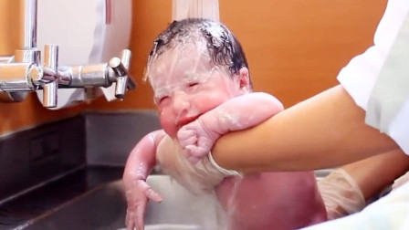 护士给新生儿洗澡，宝宝全程趴在护士手上，一脸乖巧的样子